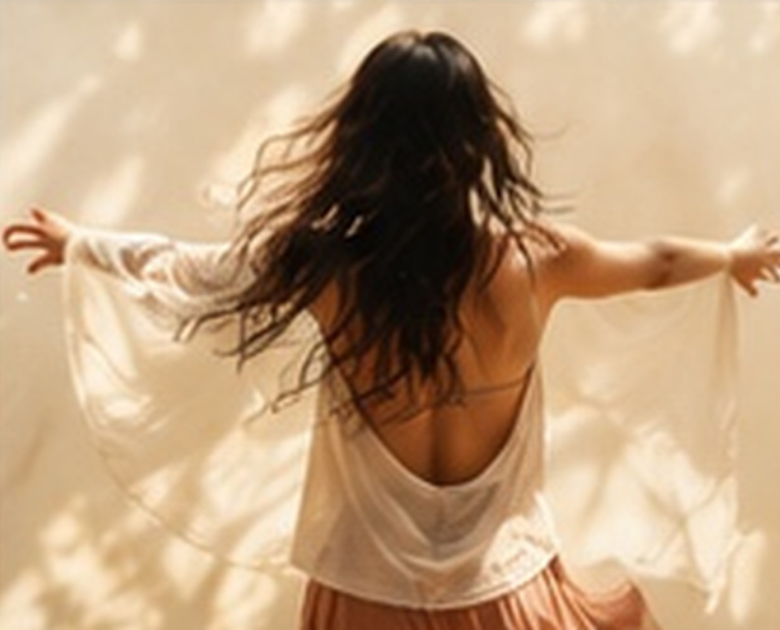 Femme dansant librement, bras ouverts, dans une lumière douce
